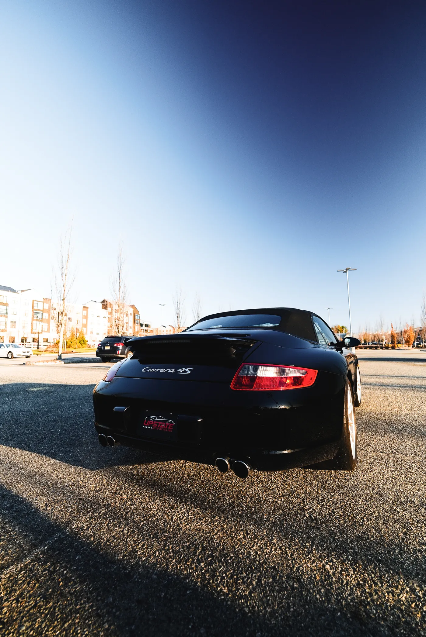 Rear view of a black Porsche Carrera 4S convertible wearing an Upstate Auto Detailing plate insert