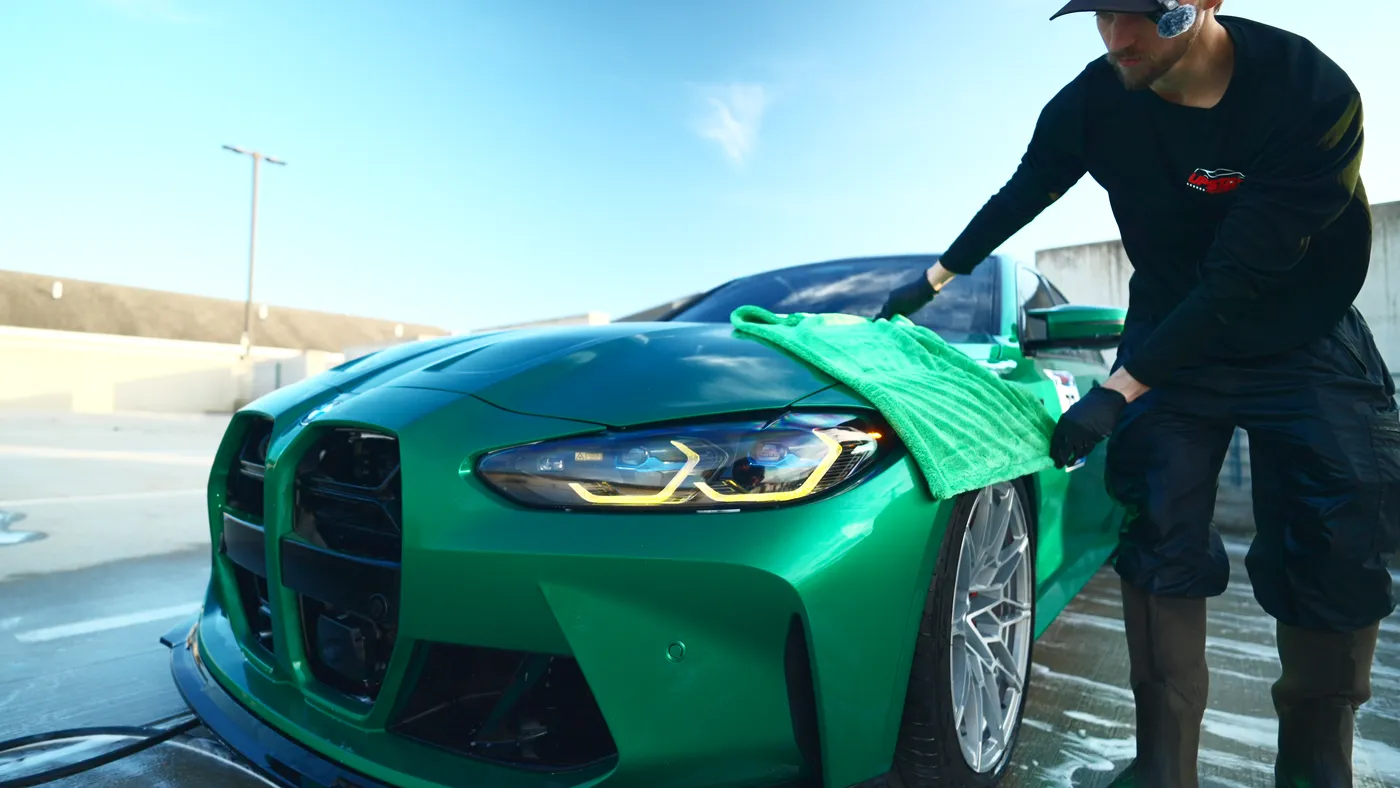 Upstate detailer drying a green BMW after an exterior wash