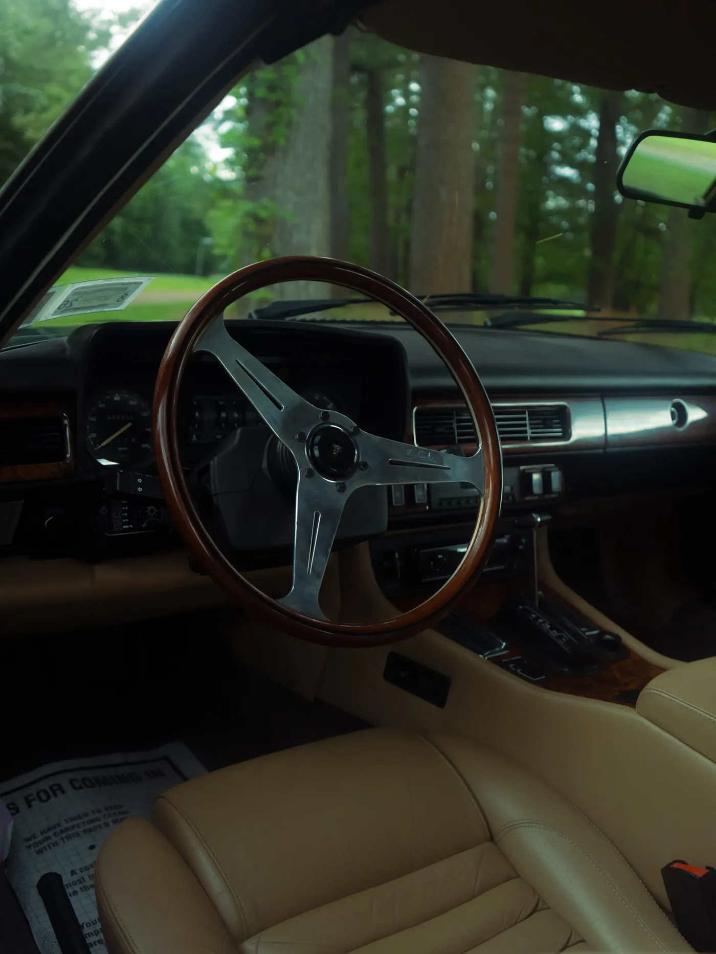 The tan leather driver's seat and wood rimmed steering wheel inside a classic Jaguar